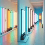 una sala museale a forma di corridoio con tanti tubi neon luminosi alle pareti messi uno dietro l\’altro in verticale
