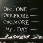 una lavagana con la scritta in gesso ONE MORE DAY